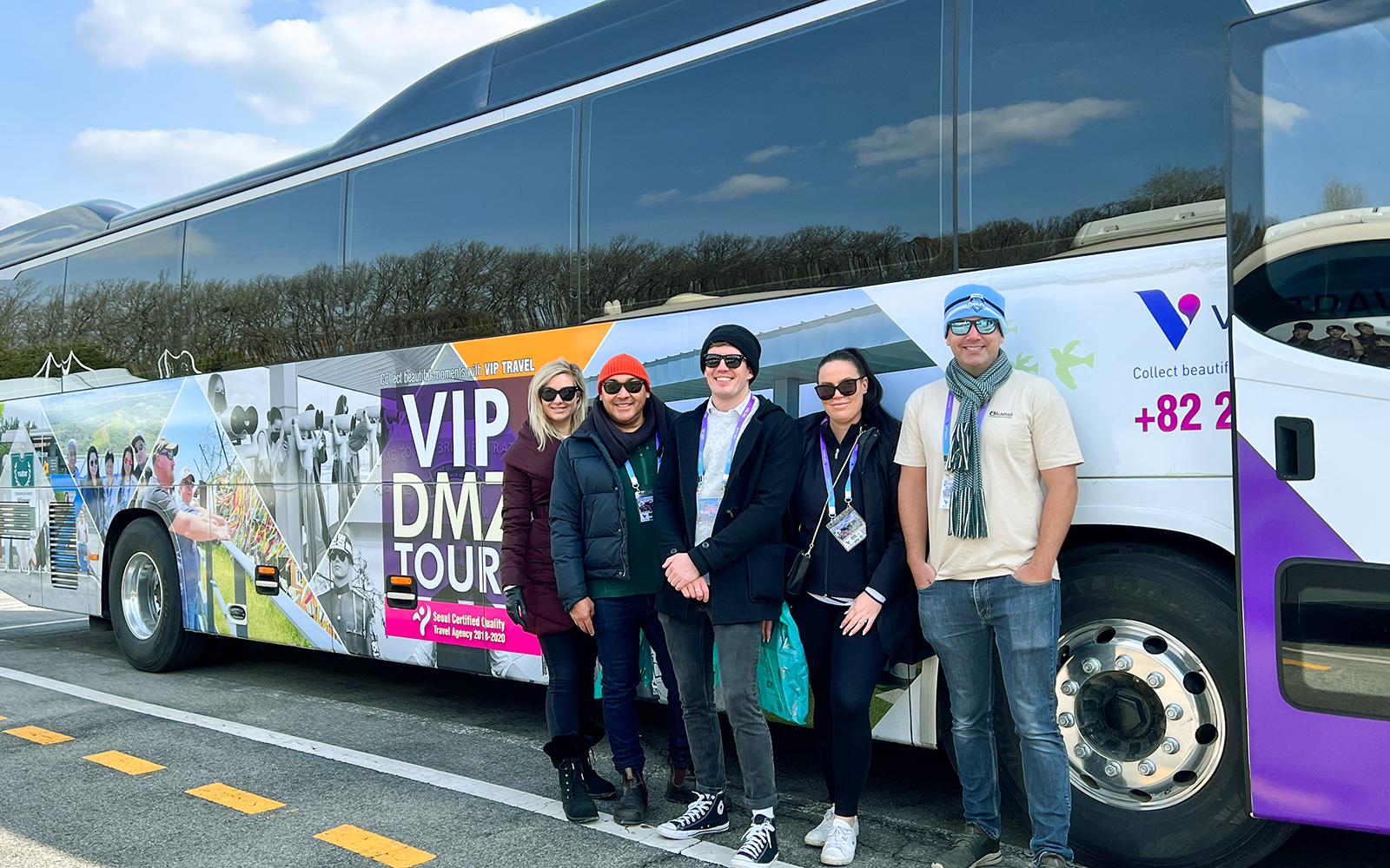 Group of tourists standing beside a VIP DMZ Tour bus in South Korea.