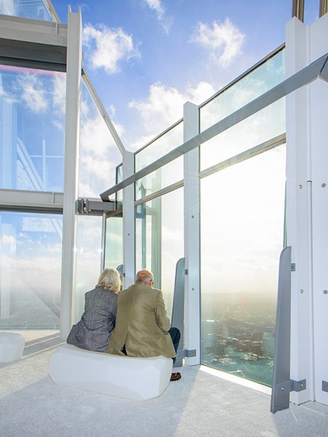 Old couple enjoying city view from The Shard's observation deck in London.