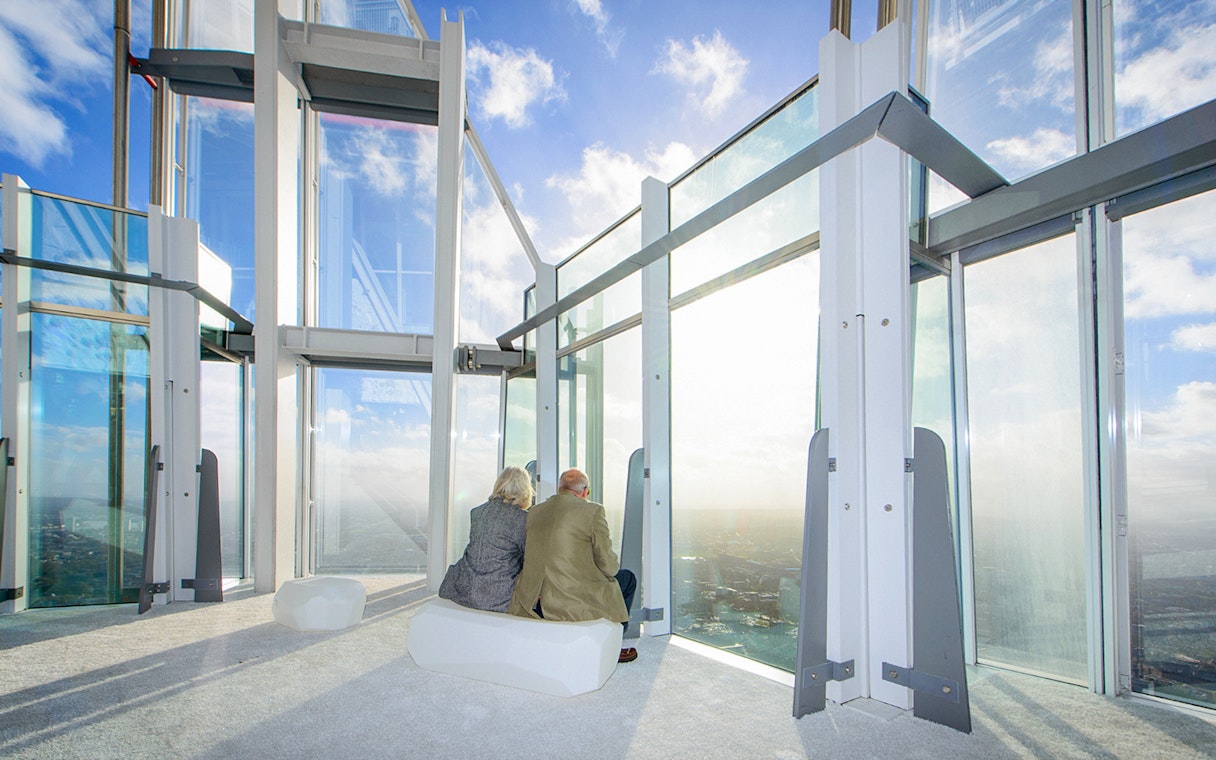 Old couple enjoying city view from The Shard's observation deck in London.