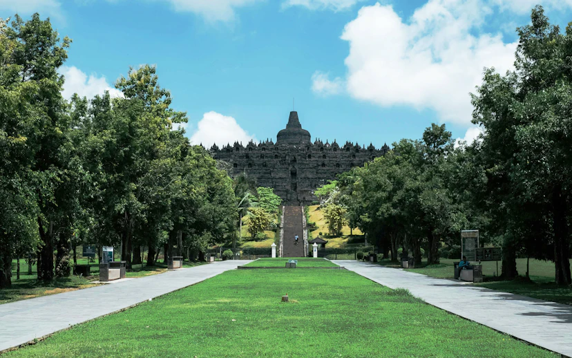 Pathway leading to Borobudur Temple surrounded by lush greenery, Indonesia.