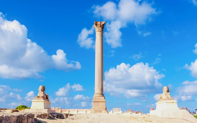 Pompey's Pillar with ancient sphinx statues in Alexandria, Egypt.