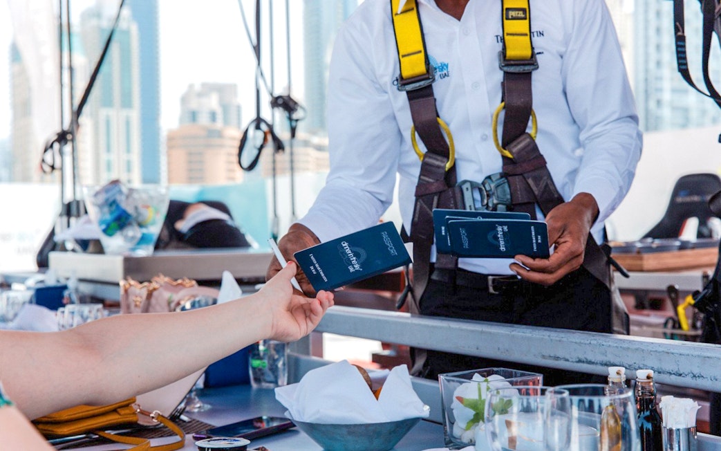 Guest receiving Dinner in the Sky tickets from staff member in harness