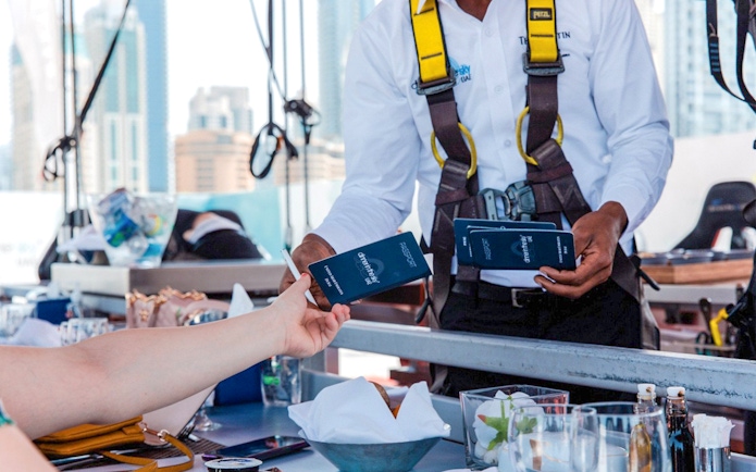 Guest receiving Dinner in the Sky tickets from staff member in harness