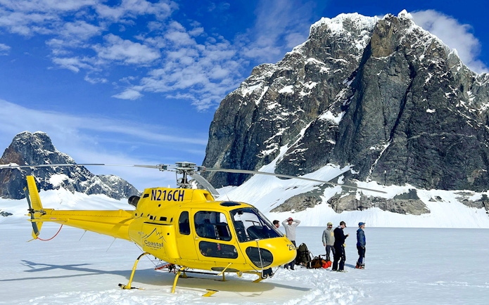 Yellow helicopter on glacier with tourists, Juneau helicopter tour, Alaska.