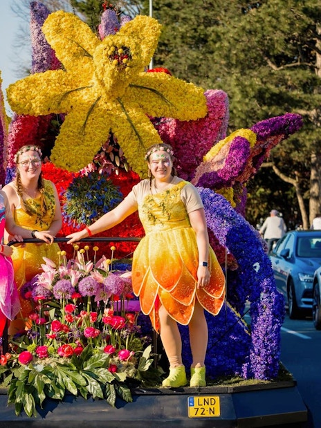 Participants in colorful costumes on a floral float at Keukenhof Flower Parade.