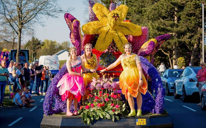 Participants in colorful costumes on a floral float at Keukenhof Flower Parade.