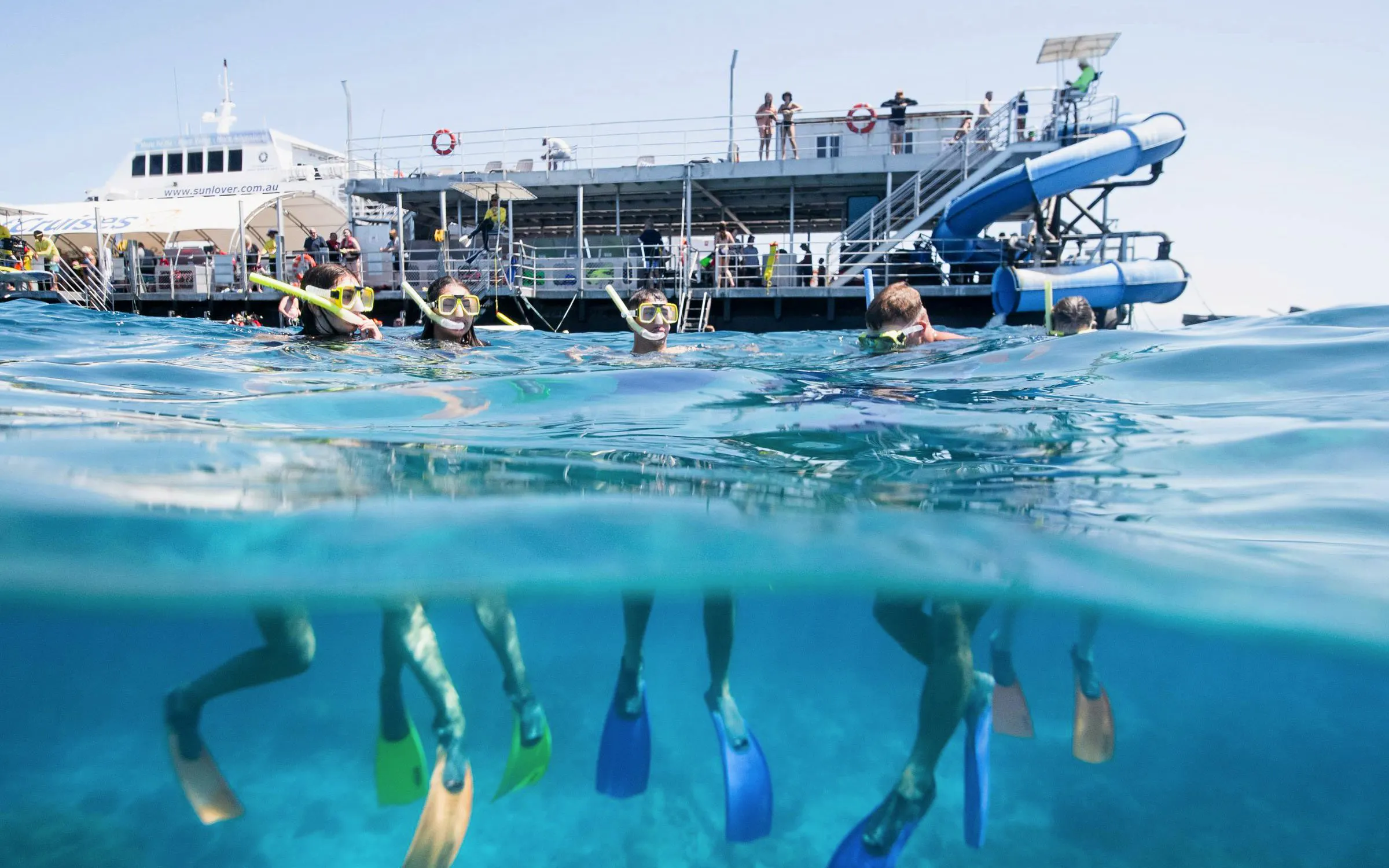 Snorkelers exploring the Great Barrier Reef with Sunlover Reef Cruises platform in the background.