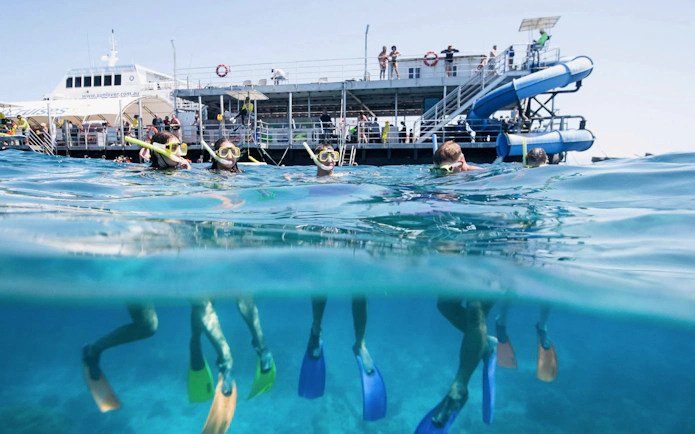 Snorkelers exploring the Great Barrier Reef with Sunlover Reef Cruises platform in the background.