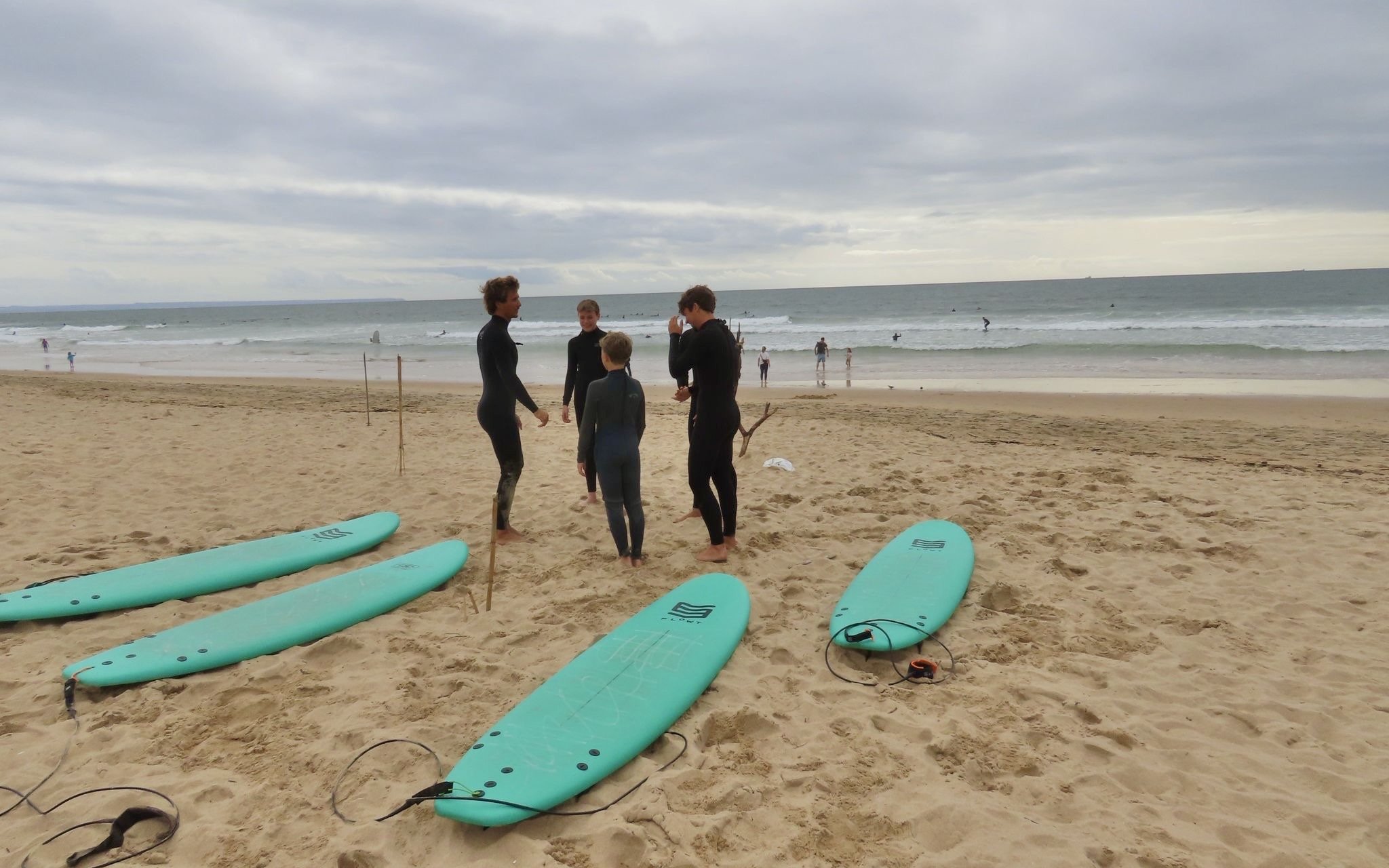 Surfers preparing on Cascais beach with surfboards and ocean in the background.