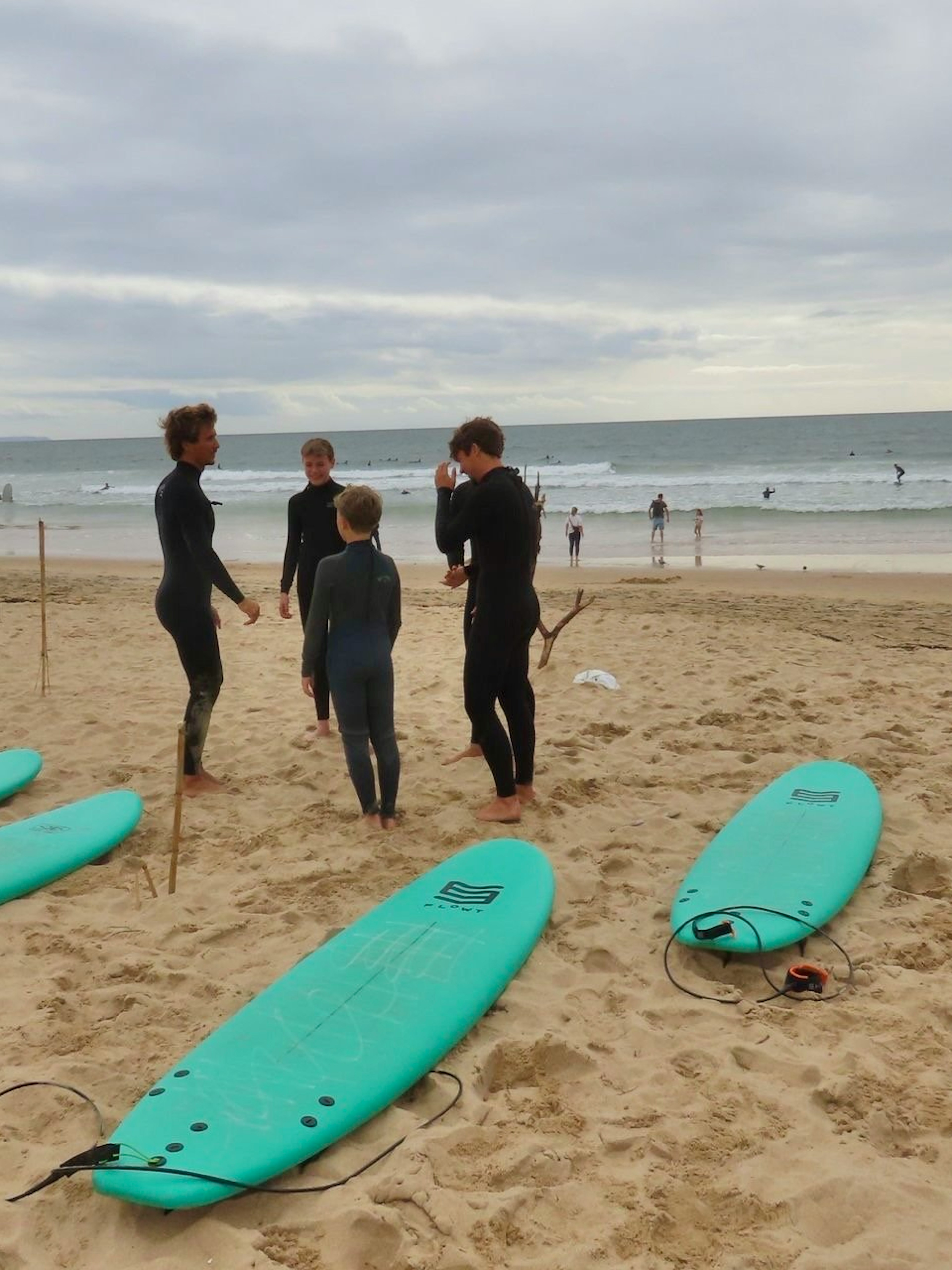 Surfers preparing on Cascais beach with surfboards and ocean in the background.