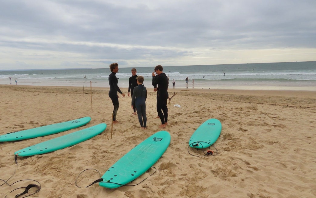 Surfers preparing on Cascais beach with surfboards and ocean in the background.