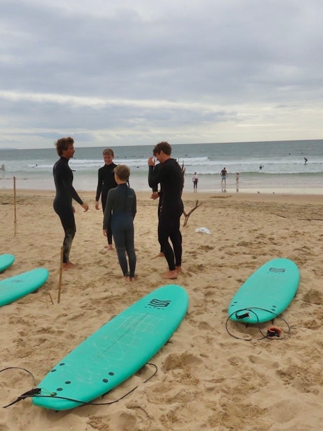 Surfers preparing on Cascais beach with surfboards and ocean in the background.