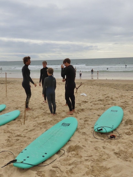 Surfers preparing on Cascais beach with surfboards and ocean in the background.
