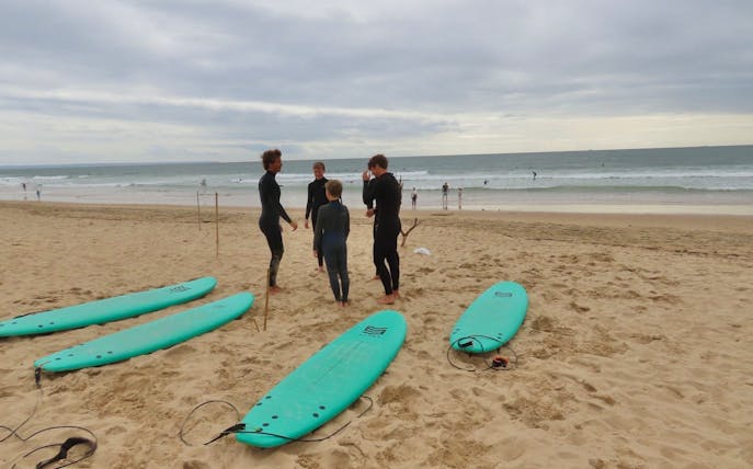 Surfers preparing on Cascais beach with surfboards and ocean in the background.