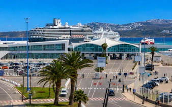 Cruise ships docked at Port of Tangier terminal with distant hills in view.
