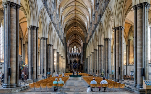 Salisbury Cathedral nave with vaulted ceilings and stained glass windows.