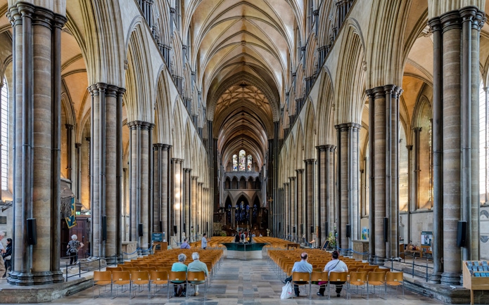 Salisbury Cathedral nave with vaulted ceilings and stained glass windows.