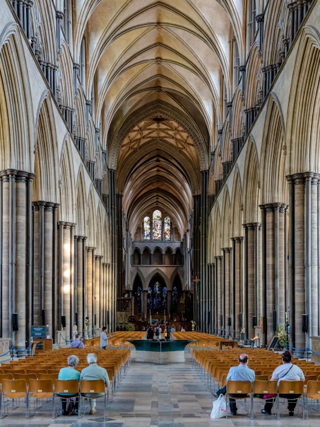 Salisbury Cathedral nave with vaulted ceilings and stained glass windows.