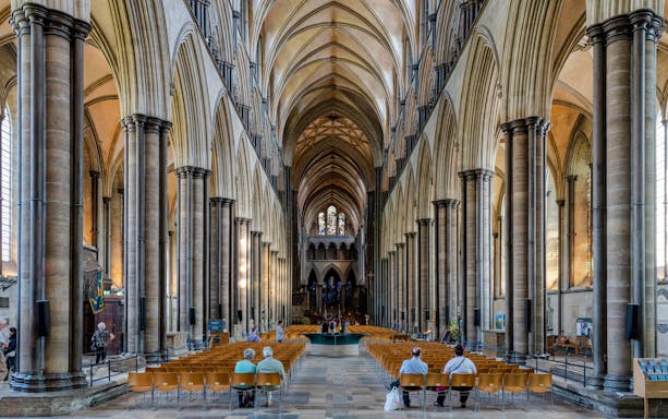 Salisbury Cathedral nave with vaulted ceilings and stained glass windows.