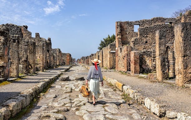 Person walking on cobbled streets of ancient Pompeii ruins, Italy.
