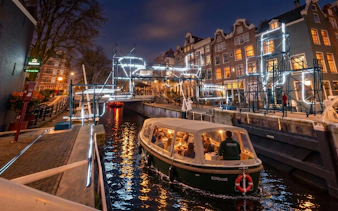 Boat tour through illuminated canals during Amsterdam Light Festival.