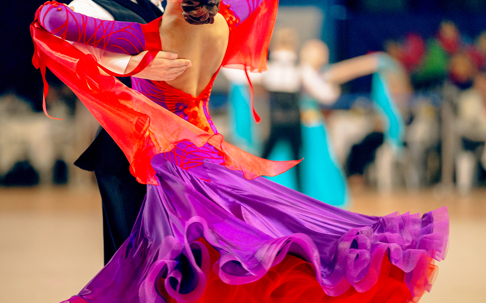 Casal dançando valsa em um grande salão de baile, exibindo movimentos de dança elegantes.