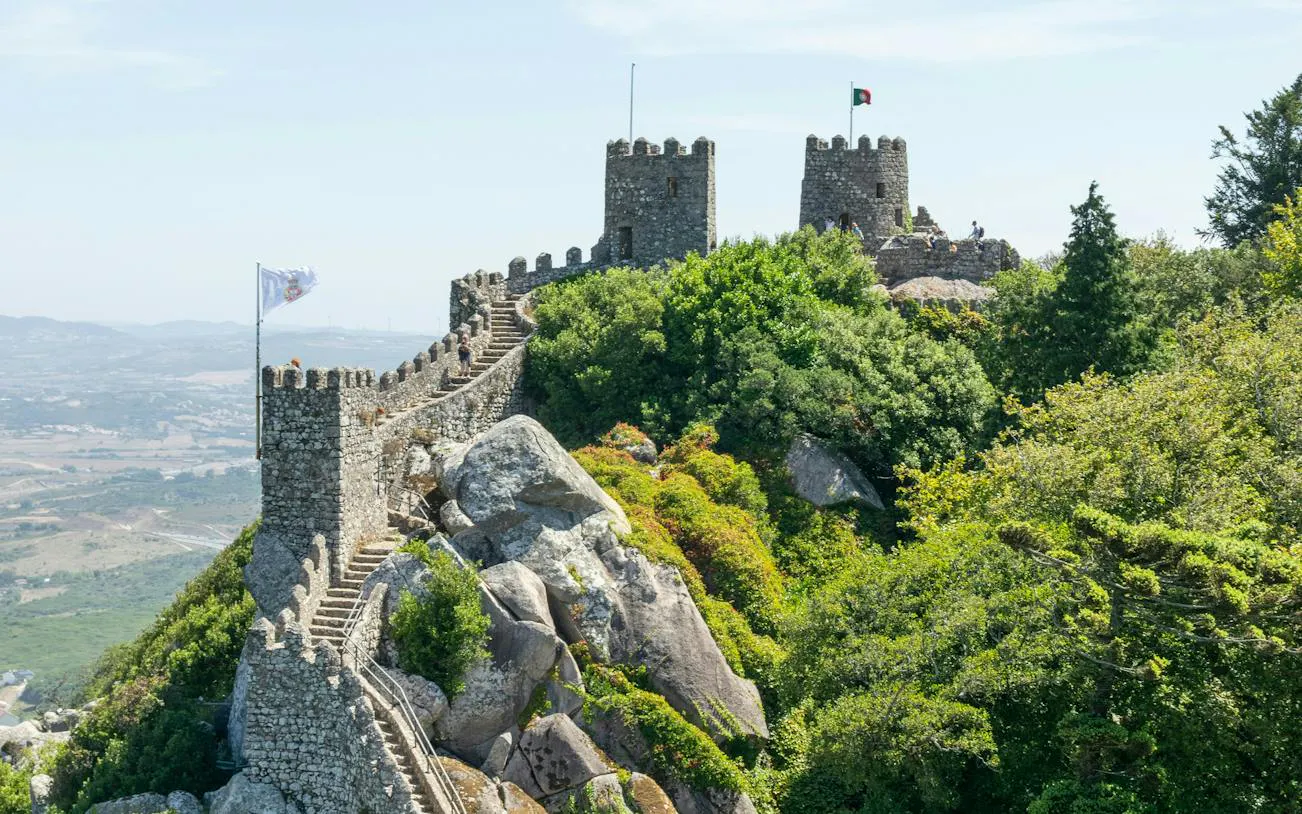Moorish Castle stone walls and towers surrounded by lush greenery in Sintra, Portugal.