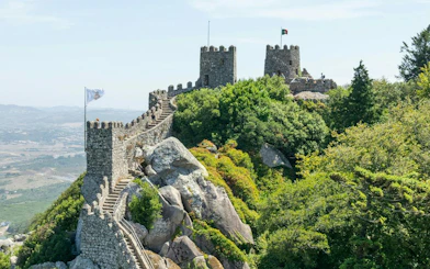 Moorish Castle stone walls and towers surrounded by lush greenery in Sintra, Portugal.