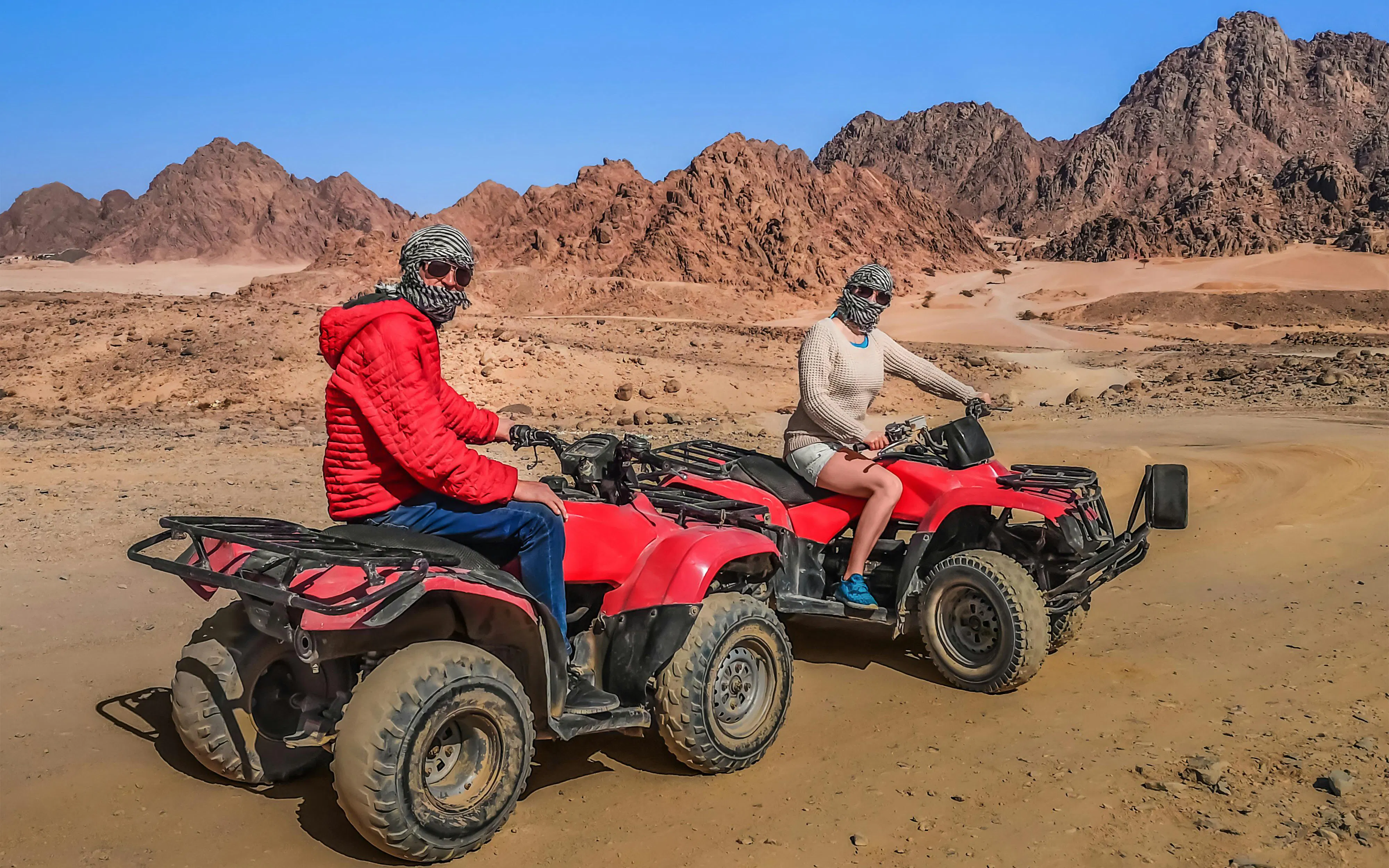 Tourists on ATVs in Echo Valley, Sharm El Sheikh, with stone mountains in the background.