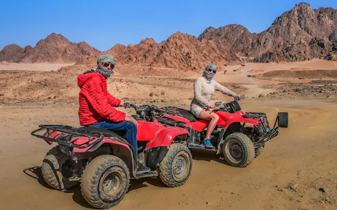 Tourists on ATVs in Echo Valley, Sharm El Sheikh, with stone mountains in the background.