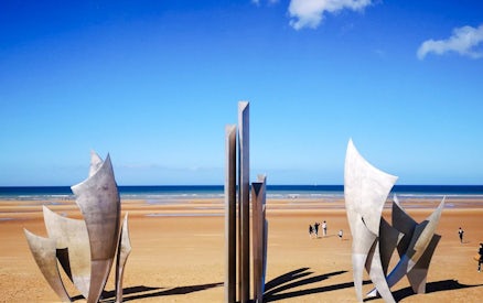Les Braves sculpture on Omaha Beach, Normandy, France with ocean backdrop.