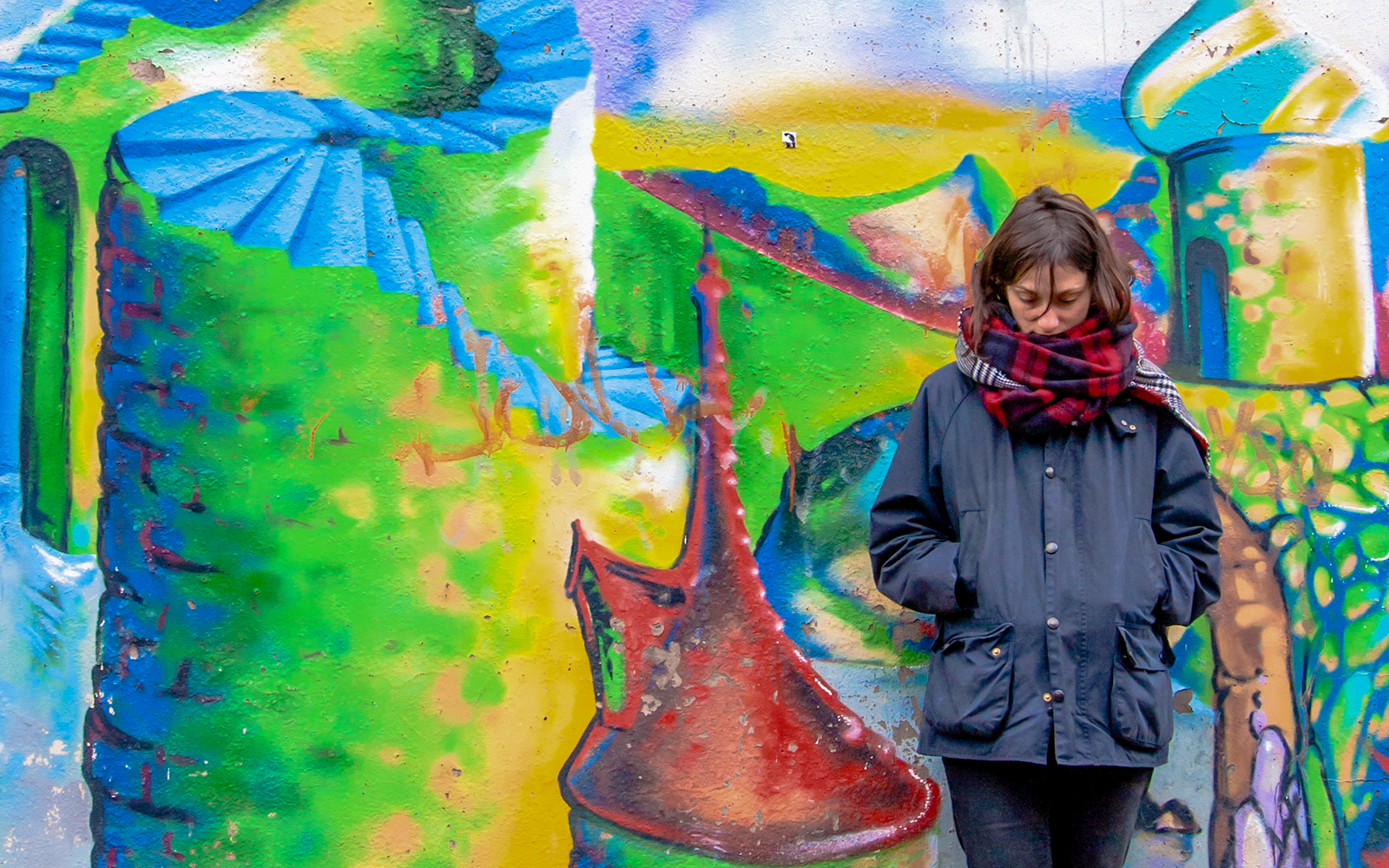 Colorful street art mural in Glasgow with a person standing in front.