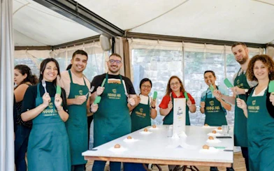 Group of people in aprons holding utensils during a cooking class in Rome.