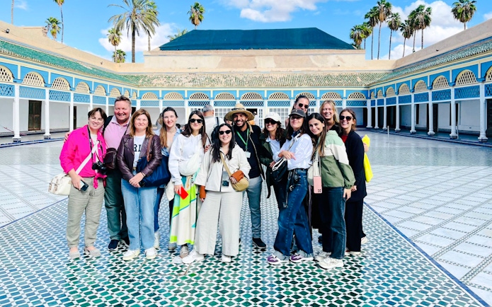 Tourists with guide at Bahia Palace courtyard in Marrakech, Morocco.