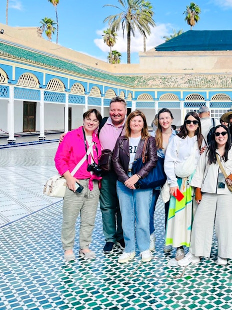 Tourists with guide at Bahia Palace courtyard in Marrakech, Morocco.