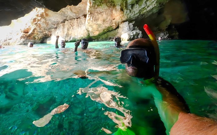 Snorkelers exploring the turquoise waters inside Haxhi Ali Cave.
