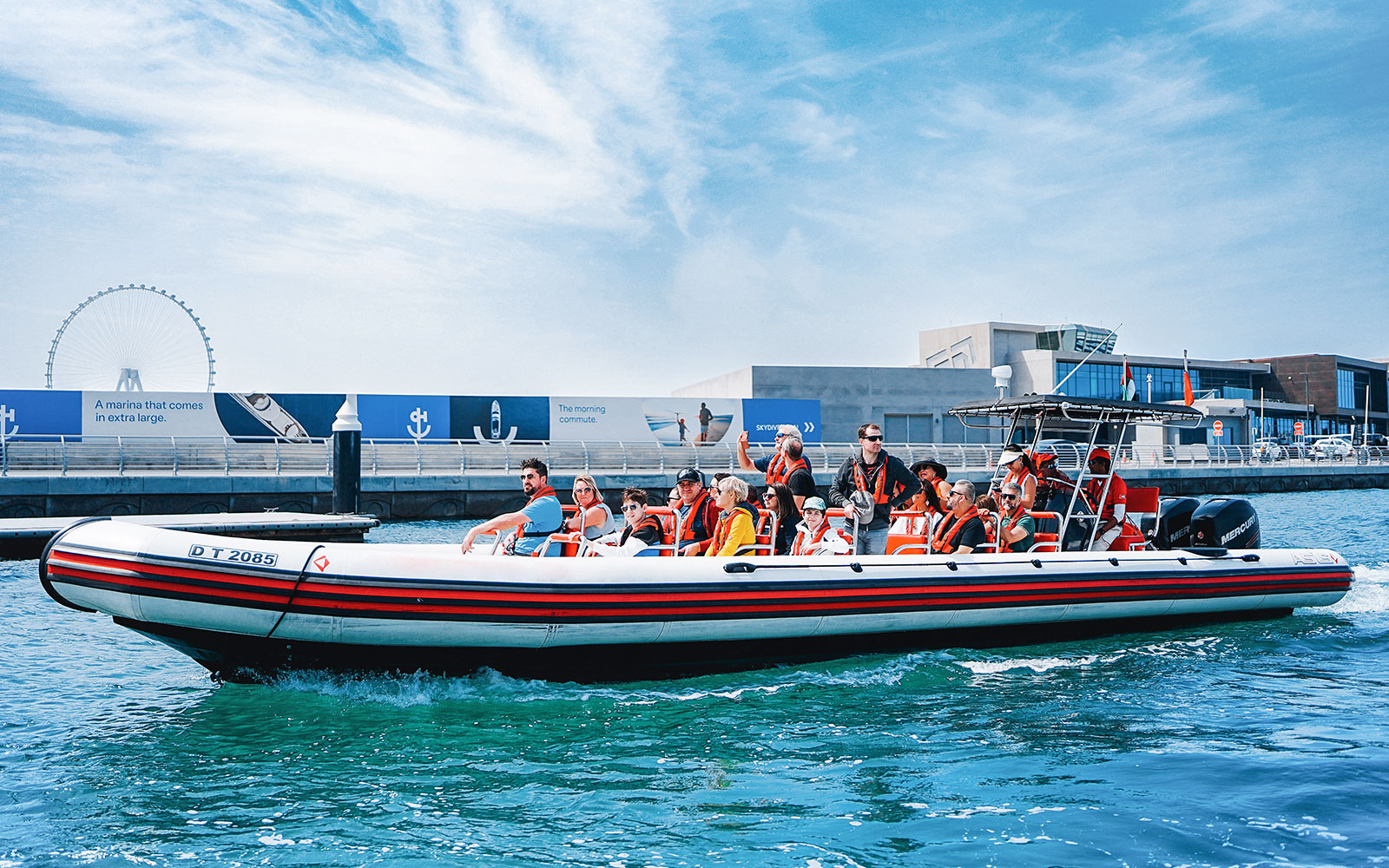 Speedboat with tourists on Dubai Marina tour, passing by waterfront attractions.