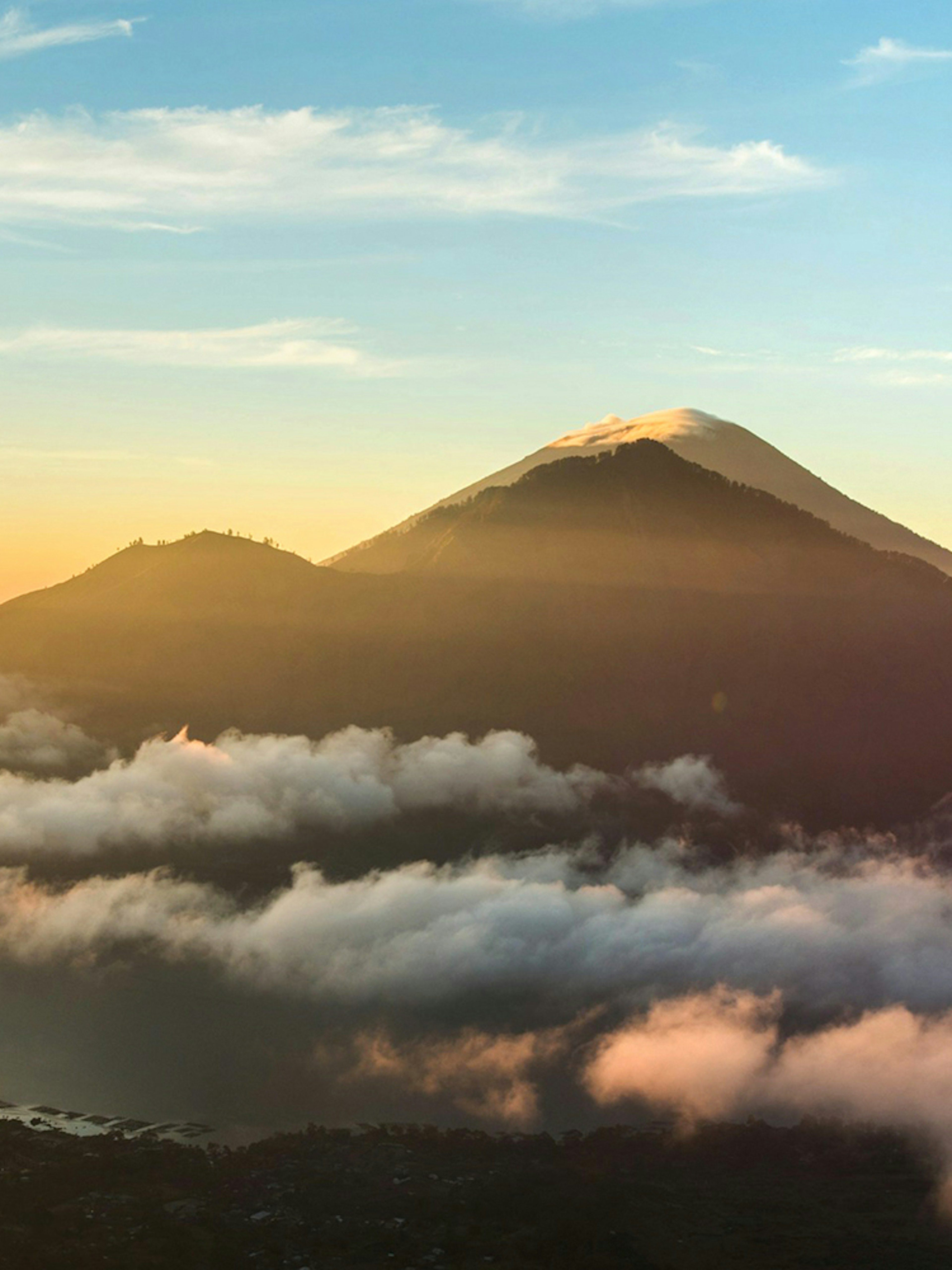 Mount Batur at sunrise with clouds and a glowing sky in Bali, Indonesia.