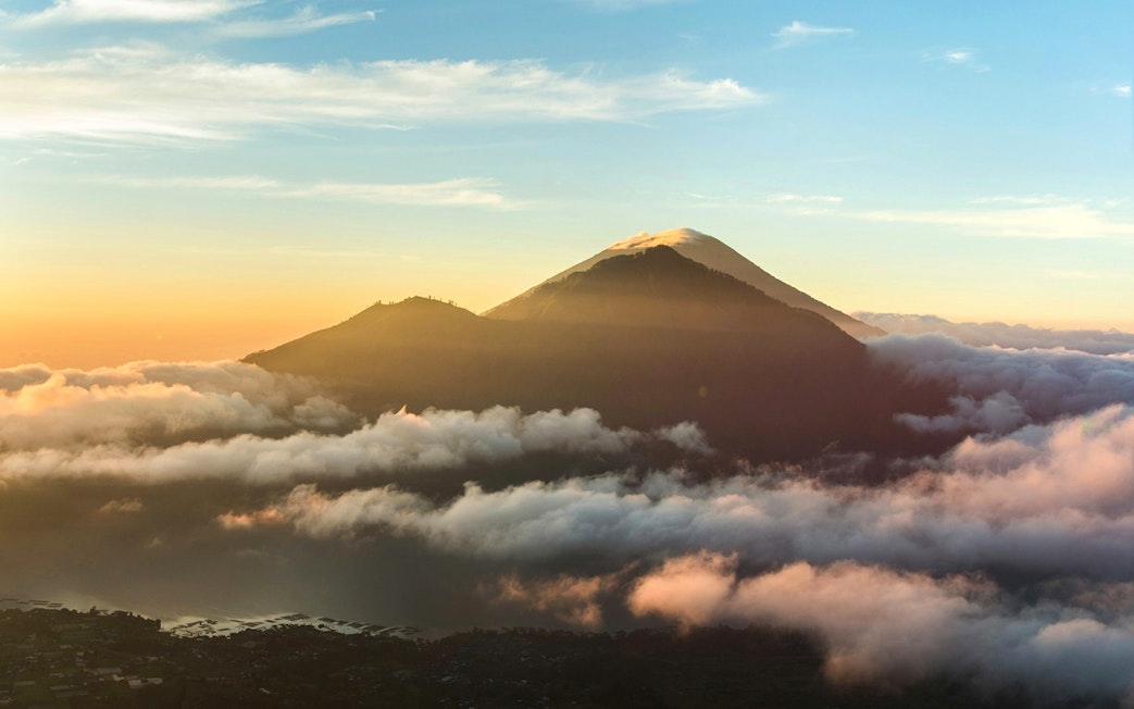 Mount Batur at sunrise with clouds and a glowing sky in Bali, Indonesia.