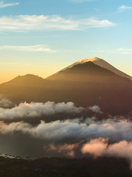Mount Batur at sunrise with clouds and a glowing sky in Bali, Indonesia.