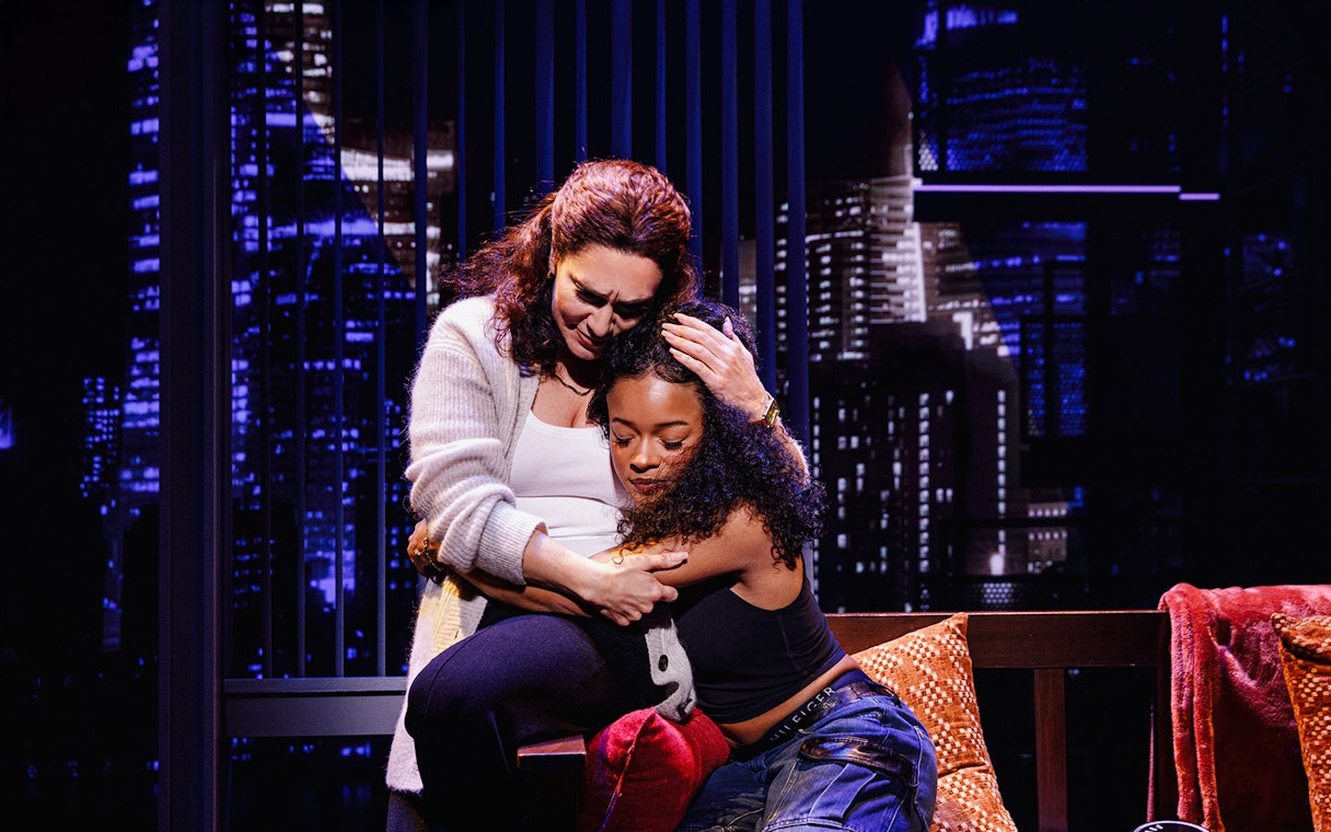 Two people embracing in front of a cityscape backdrop in Hell's Kitchen.