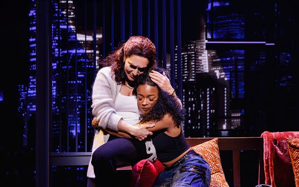 Two people embracing in front of a cityscape backdrop in Hell's Kitchen.