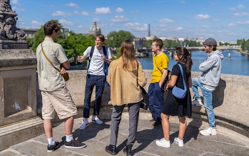 Participants on a guided tour of Notre Dame islands, standing on a bridge overlooking the Seine River.