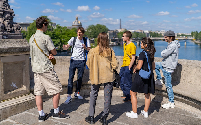 Participants on a guided tour of Notre Dame islands, standing on a bridge overlooking the Seine River.