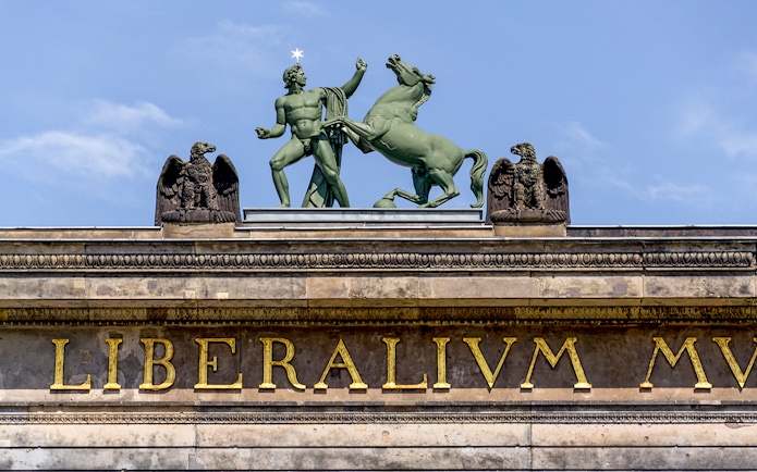 Statue of a man and horse atop Altes Museum in Berlin, Germany.