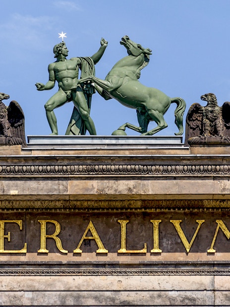 Statue of a man and horse atop Altes Museum in Berlin, Germany.