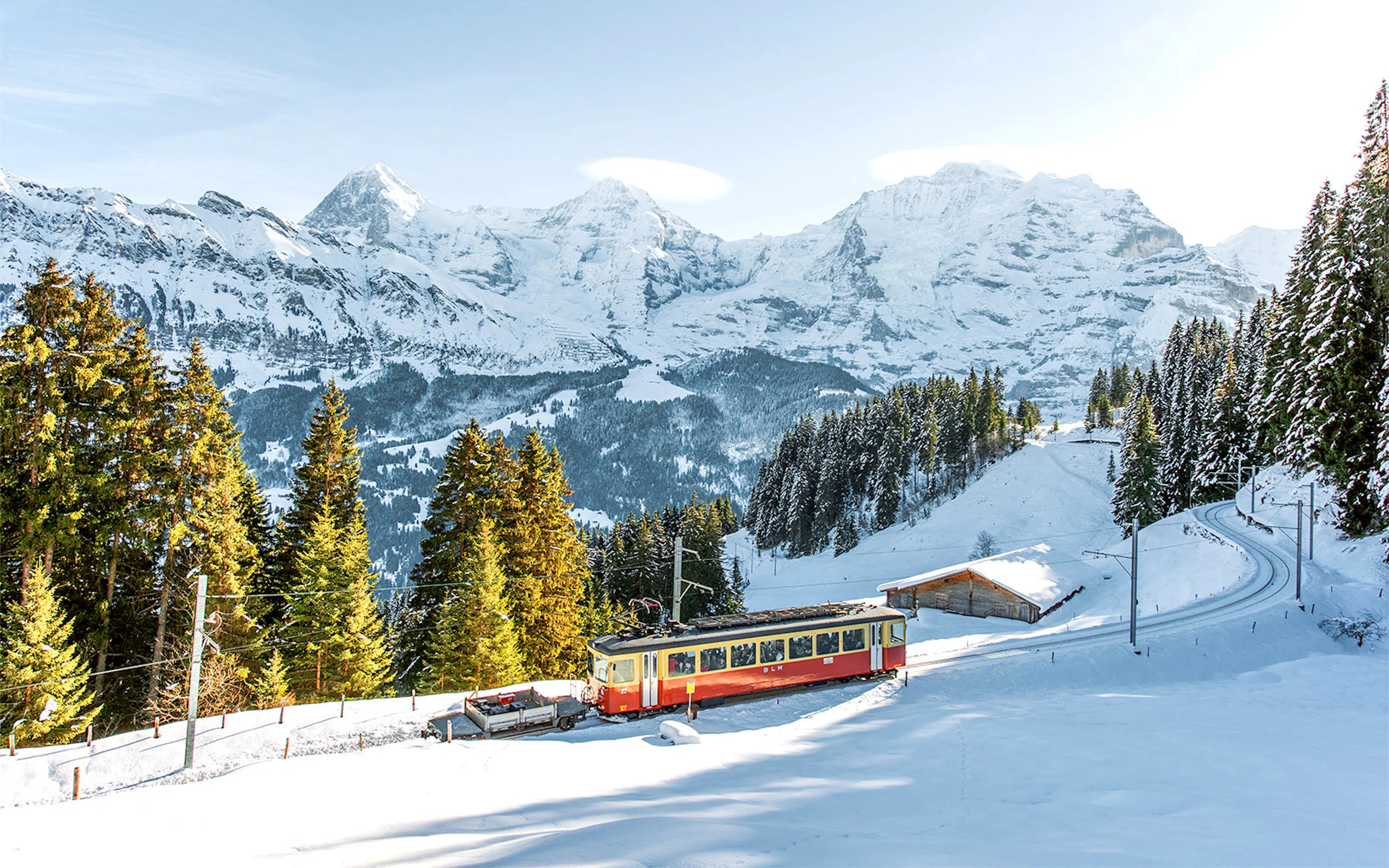 Train traveling through snowy landscape from Interlaken to Jungfraujoch with mountain views.