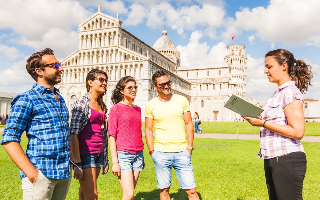 Tour group with guide in front of Pisa Cathedral and Baptistery, Italy.
