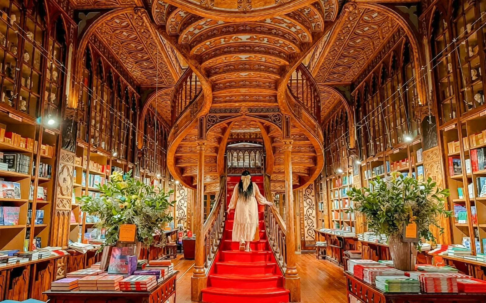 Livraria Lello's iconic red staircase with ornate woodwork in Porto, Portugal.