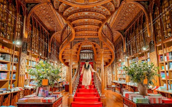 Livraria Lello's iconic red staircase with ornate woodwork in Porto, Portugal.